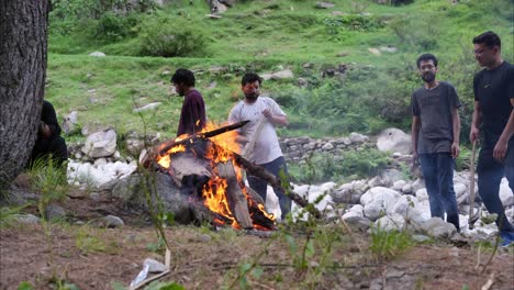 Timelapse-De-Una-Fogata-Ardiendo-En-Un-Bosque,-Con-Un-Grupo-De-Personas-Paradas-Y-Trabajando-Alrededor-De-Ella.