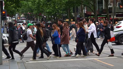 A-bustling-city-crosswalk-filled-with-diverse-pedestrians-crossing-the-road,-some-on-phones,-others-with-bags,-captures-vibrant-urban-life,-slow-motion-shot-at-Lonsdale-and-Swanston-Streets