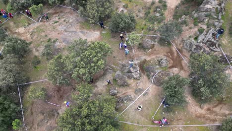 Vuelo-Con-Vista-Cenital-En-Un-Circuito-De-Motocross-Donde-Se-Celebra-Un-Campeonato-Vemos-Pilotos-Actuando-Con-Motos-Y-Motociclistas-A-Pie-El-Circuito-De-Actuación-Está-Marcado-Con-Cinta-Blanca