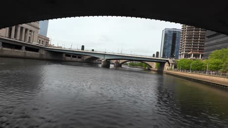 Aerial-FPV-shot-under-bridge-revealing-30th-Street-Station-in-downtown-Philadelphia,-PA-with-Schuylkill-River