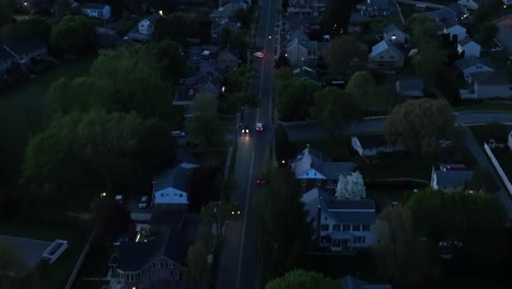 Aerial-tracking-shot-of-police-car-on-main-street-of-small-american-town-at-dusk
