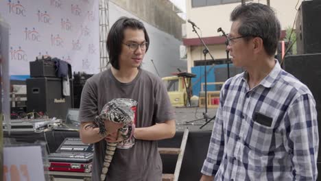 Man-showing-an-Argentine-black-and-white-tegu-lizard-to-an-older-man-at-an-outdoor-event