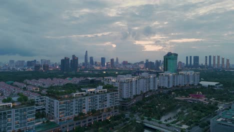 Aerial-Evening-View-of-Ho-Chi-Minh-City-Skyline-from-Sala,-a-modern-luxurious-development-with-park-and-lake-near-the-Saigon-River