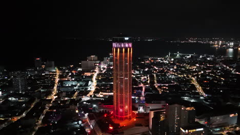Aerial-view-around-the-illuminated-Komtar-Tower,-night-in-George-Town,-Malayisa