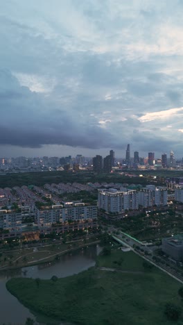 Aerial-Evening-tracking-View-of-Ho-Chi-Minh-City-Skyline-from-Sala,-a-modern-luxurious-development-with-park-and-lake-near-the-Saigon-River