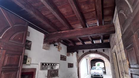 Car-passing-through-the-wooden-door-and-arched-passageway-underneath-the-houses-in-Verona,-Italy