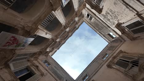 Vista-Giratoria-Dentro-Del-Palazzo-Palmieri-Con-Un-Cielo-Azul-Claro-Visible-Arriba,-Rodeado-Por-Los-Muros-Del-Palacio,-Monopoli,-Italia