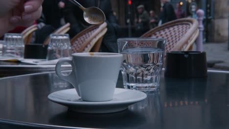 Woman-stirring-and-sipping-her-espresso-on-a-terrace-in-Paris