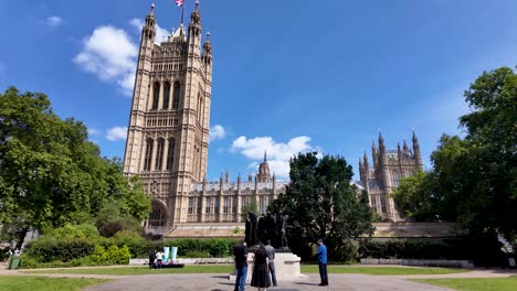 Tourists-visiting-the-Victoria-Tower-in-Westminster-and-admiring-the-Burghers-of-Calais-statue-in-Victoria-Gardens,-London-on-a-bright,-sunny-day