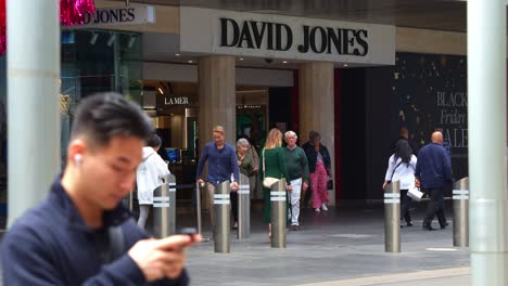 Foot-traffic-of-the-front-entrance-of-David-Jones-premium-department-store-in-bustling-downtown-Melbourne-city,-slow-motion-shot-capturing-the-pedestrians-strolling-along-Bourke-Street-Mall