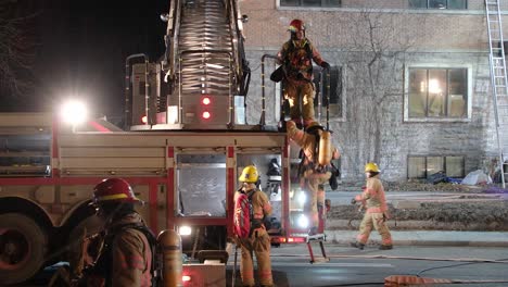 Firefighters-pack-up-rolling-fire-hoses-and-climbing-down-ladder-after-reporting-to-abandoned-building-emergency