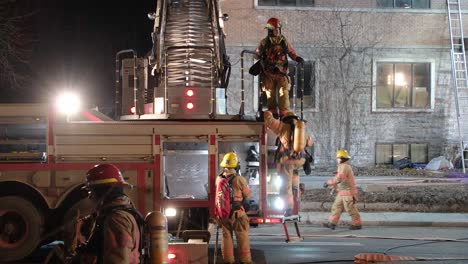 Feuerwehrleute-Packen-Aufgerollte-Feuerwehrschläuche-Ein-Und-Klettern-Die-Leiter-Hinunter,-Nachdem-Sie-Den-Notfall-In-Einem-Verlassenen-Gebäude-Gemeldet-Haben