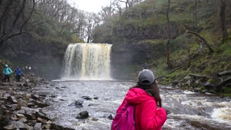 La-Mujer-Disfruta-De-La-Vista-De-La-Cascada-Sgwd-Año-Eira-En-El-Parque-Nacional-De-Brecon-Beacons,-Gales