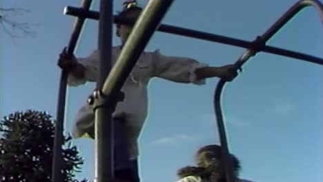1970S-SCHOOL-GIRLS-CLIMBING-ON-PLAY-EQUIPMENT-DURING-RECESS
