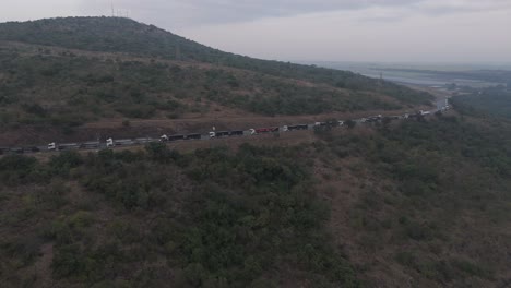 Vista-Por-Drones-De-Camiones-Haciendo-Cola-Para-El-Puesto-Fronterizo-En-Una-Larga-Fila-A-Través-Del-Paisaje-Accidentado