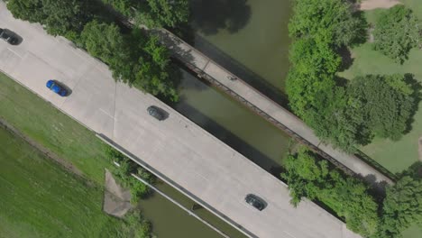 An-aerial-top-down-drone-view-of-an-adult-male-cycling-over-the-Big-Island-Slough-on-the-Armand-Bayou-Hike-and-Bike-Trail-in-Pasadena,-Texas