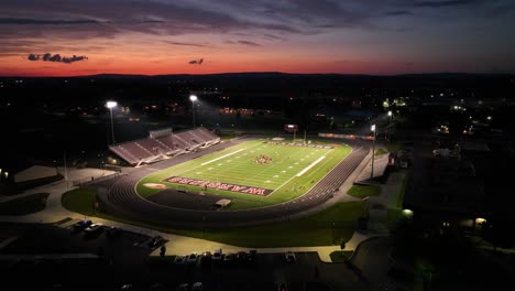 Aerial-approaching-shot-of-Football-Stadium-in-american-town-during-golden-sunset