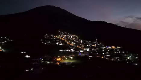 Aerial-view-of-lights-from-houses-in-villages-on-the-slopes-of-the-mountain-in-foggy-morning-dawn