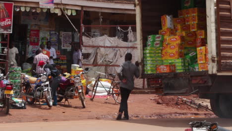 Hombre-Descargando-Cajas-De-Un-Camión-En-Un-Concurrido-Mercado