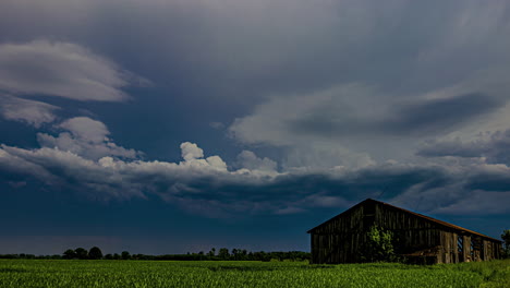 Timelapse-of-dark-clouds-formation-before-a-storm-with-a-wodden-shed-and-green-grass-on-the-foreground