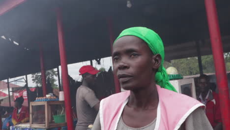 A-woman-in-a-pink-apron-stands-in-a-busy-outdoor-market-in-Africa