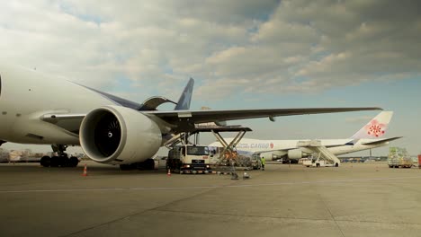 Ground-crew-working-around-parked-cargo-planes-at-an-airport,-busy-with-loading-and-unloading-operations