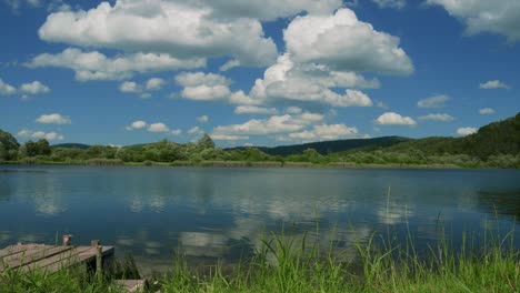 Push-in-Timelapse-of-lakeside-with-a-vibrant-blue-sky,-fluffy-clouds