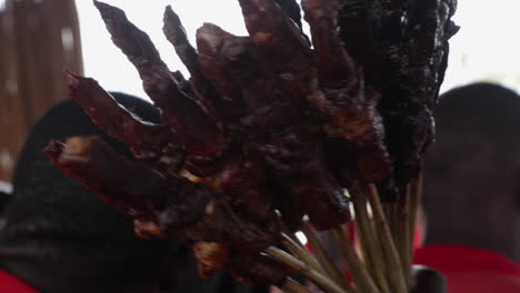 Grilled-skewers-of-meat-held-by-a-vendor-at-an-outdoor-market