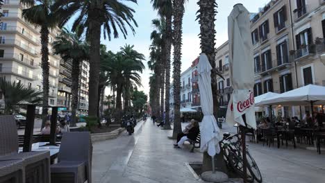 Walking-POV-in-Bari,-surrounded-by-tall-palm-trees,-Italy,-Europe