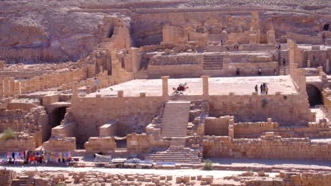 Elevated-view-overlooking-the-Great-Temple-Nabatean-building-ruins-with-tourist-visiting-and-exploring-the-ancient-city-of-Petra-in-Jordan