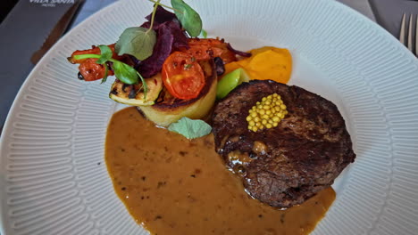 Close-up-shot-of-creamy-reindeer-and-vegetable-dish-on-white-plate-at-a-restaurant-table