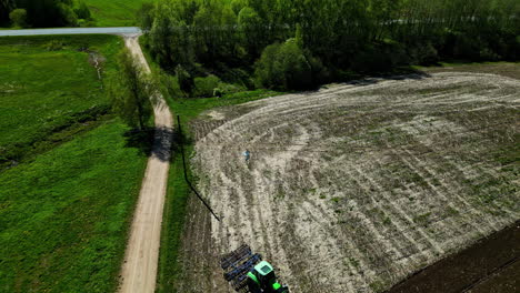 Green-tractor-ploughs-field,-aerial-establisher-agriculture-farmland