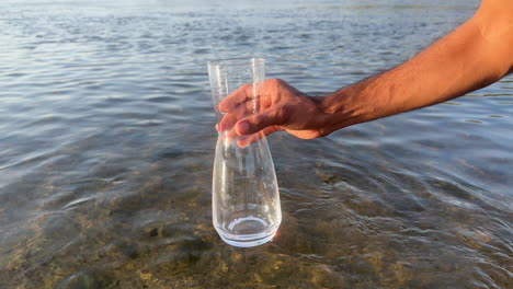 Kamera-Unter-Wasser-Fallen-Lassen,-Während-Eine-Hand-Ein-Glas-Mit-Frischem-Wasser-Füllt