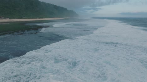 Slow-Motion-Drone-of-sunset-wave-action-at-low-tide-over-coral-and-rock-reef-Nyang-Nyang-Beach,-Bali,-Uluwatu-Indonesia