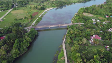 Río-Pajo-Con-Aguas-Tranquilas-A-Lo-Largo-De-Las-Tierras-De-Cultivo,-Casas-Y-Paisajes-Verdes-En-Virac,-Catanduanes,-Filipinas