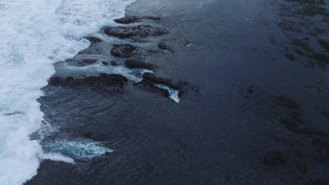 Drone-De-Arriba-Hacia-Abajo-De-La-Acción-De-Las-Olas-Durante-La-Marea-Baja-Sobre-Arrecifes-De-Coral-Y-Rocas-En-La-Playa-De-Nyang-Nyang,-Bali,-Uluwatu,-Indonesia