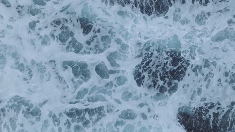 Top-Down-Slow-Motion-Drone-of-wave-action-at-low-tide-over-coral-and-rock-reef-Nyang-Nyang-Beach,-Bali,-Uluwatu-Indonesia