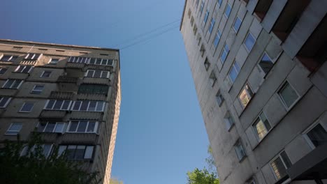 Low-angle-POV-floating-through-a-concrete-ghetto-suburb-with-towering-high-apartment-blocks