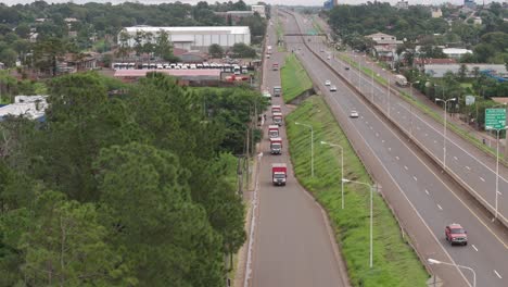 Toma-De-Drone-De-La-Carretera-Colectora-En-Primer-Plano-Capturando-Camiones,-Mostrando-La-Infraestructura-Y-Detallando-La-Dinámica-Del-Transporte.