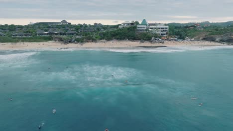 Drone-of-Dreamland-Beach,-Bali,-Uluwatu-Indonesia-at-golden-hour-sunset-with-turquoise-water-and-surfers