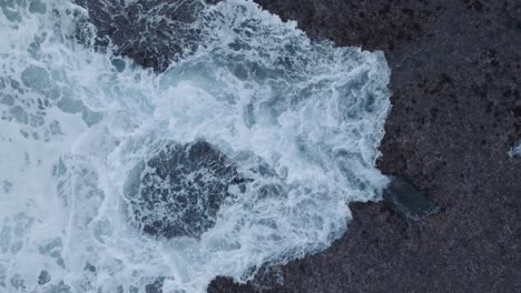 Drone-En-Cámara-Lenta-De-Arriba-Hacia-Abajo-De-La-Acción-De-Las-Olas-Durante-La-Marea-Baja-Sobre-Arrecifes-De-Coral-Y-Rocas-En-La-Playa-De-Nyang-Nyang,-Bali,-Uluwatu-Indonesia