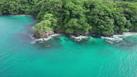 Aerial-Flyover-Turquoise-Blue-Ocean-With-Green-Trees-On-Cliffs,-Penca-Beach,-Costa-Rica-4K-Drone