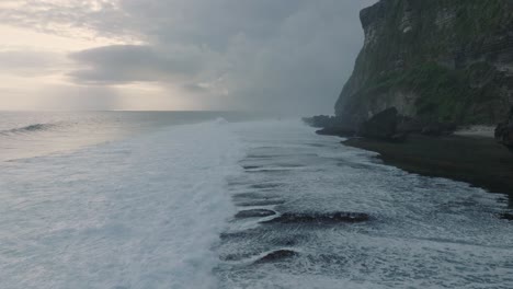 Slow-Motion-Drone-of-sunset-wave-action-at-low-tide-over-coral-and-rock-reef-Nyang-Nyang-Beach,-Bali,-Uluwatu-Indonesia