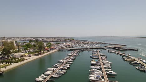 Speedboat-and-fishing-boats-lined-up-in-slips-of-dock-in-protected-harbor-of-Olhao-Portugal