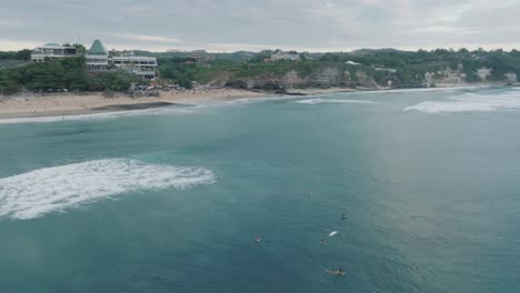 Drone-of-Dreamland-Beach,-Bali,-Uluwatu-Indonesia-at-golden-hour-sunset-with-turquoise-water-and-surfers