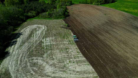 Tractor-Verde-Con-Arado-Arado-Pistas-En-El-Campo,-órbita-Aérea-Día-Soleado