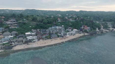 High-Angle-Drone-of-Bingin-Beach,-Bali,-Uluwatu-Indonesia-at-golden-hour-sunset-with-low-tide-reef-and-surfers