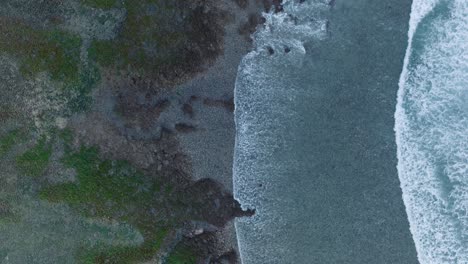 Drone-En-Cámara-Lenta-De-Arriba-Hacia-Abajo-De-La-Acción-De-Las-Olas-Durante-La-Marea-Baja-Sobre-Arrecifes-De-Coral-Y-Rocas-En-La-Playa-De-Nyang-Nyang,-Bali,-Uluwatu-Indonesia