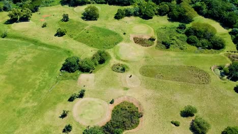 Aerial-footage-of-a-drone-moving-over-a-golf-course-and-a-highway