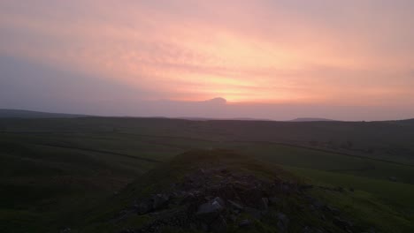 A-steady-flight-over-the-rocky-hill-on-a-pink-smokey-sunset-at-Erwood-Reserve,-UK